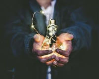 photo of hands holding a sparking light bulb